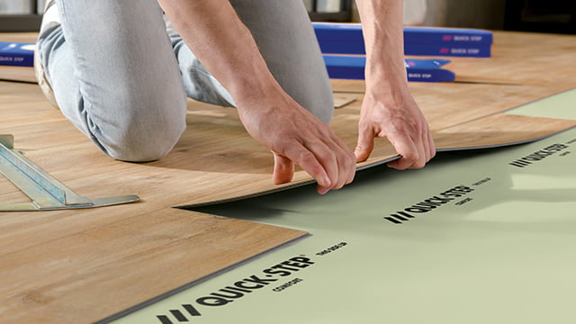 man installeert een click vinyl vloer op een ondervloer